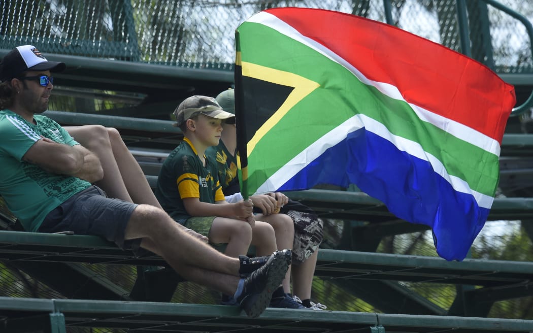A young cricket fan holds the South African national flag during the third day of the fourth Test cricket match between South Africa and England at the Wanderers Stadium in Johannesburg on January 26, 2020. (Photo by Christiaan Kotze / AFP)