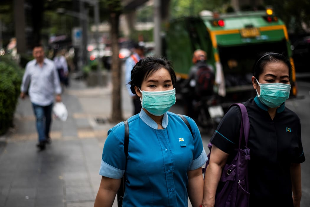 Pedestrians wearing face masks make their way along a street in Bangkok today.