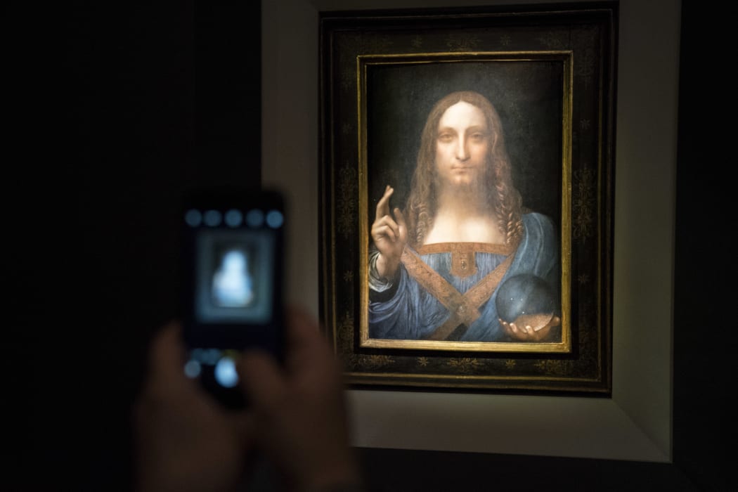A visitor takes a photo of the painting 'Salvator Mundi' by Leonardo da Vinci at Christie's New York Auction House, November 15, 2017 in New York City.