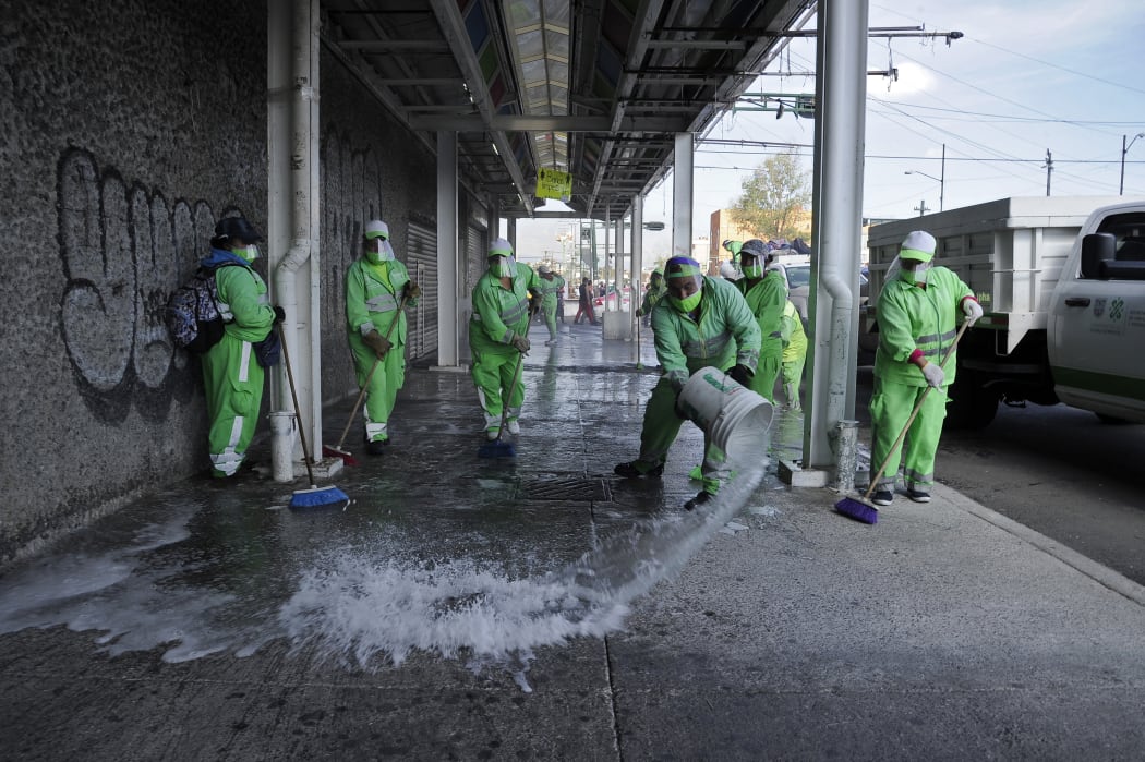 Municipal workers clean and disinfect a sidewalk in Tepito neighborhood in Mexico City