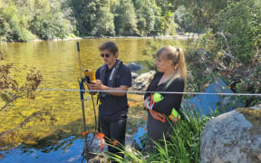 Hydrology manager Samwell Warren and WCRC Environmental Science manager Shanti Morgan setting up cable to record baseline flows in river.