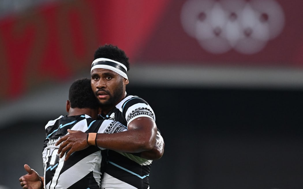 Fiji's Napolioni Bolaca (L) hugs Vilimoni Botitu after winning the men's final rugby sevens match between New Zealand and Fiji during the Tokyo 2020 Olympic Games at the Tokyo Stadium in Tokyo on July 28, 2021. (Photo by Ben STANSALL / AFP)