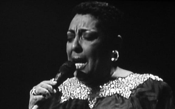 Jazz singer Carmen McRae holding a microphone, eyes closed, and singing