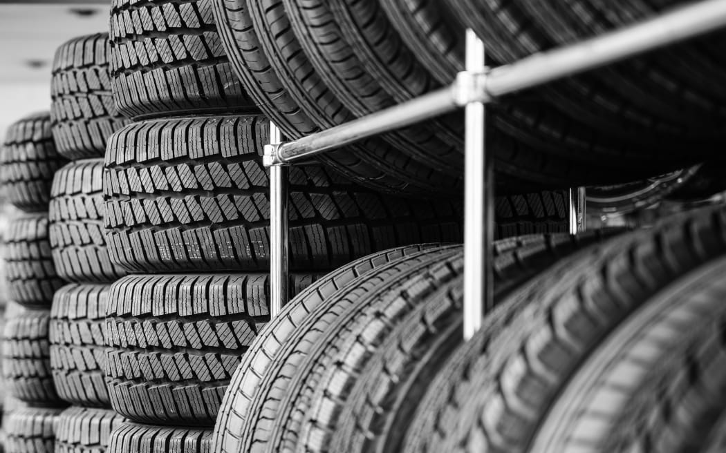Rack with variety of new car tires in automobile store, selective focus