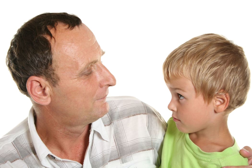 A photo of a grandfather and a boy looking into each others' eyes and sharing a thoughtful moment