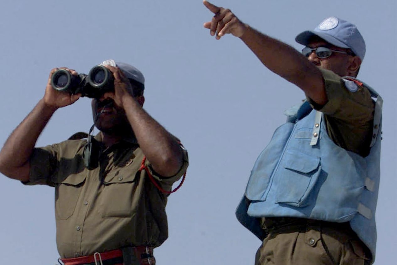 A Fijian UN peacekeeper looks through binoculars at an Israeli post from the Al-Labbouneh hill near Naqoura on the Mediterranean coast 30 July 2000 where fifty Fijian troops took up position.