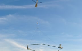 A helicopter with aerial electromagnetic (AEM) technology taking off.