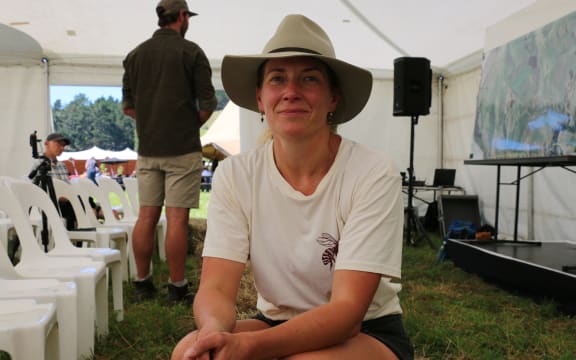 Underground Festival organiser Fran Bailey sits on a hay bale inside a tent at the event. There are people milling about in the background.