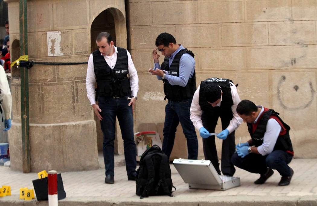 Egyptian security members and forensic police inspect the site of a gun attack outside a church south of the capital Cairo, on December 29, 2017.