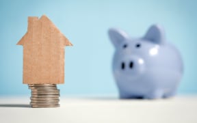 Illustration of savings with coins, a piggy bank and a model of a house.