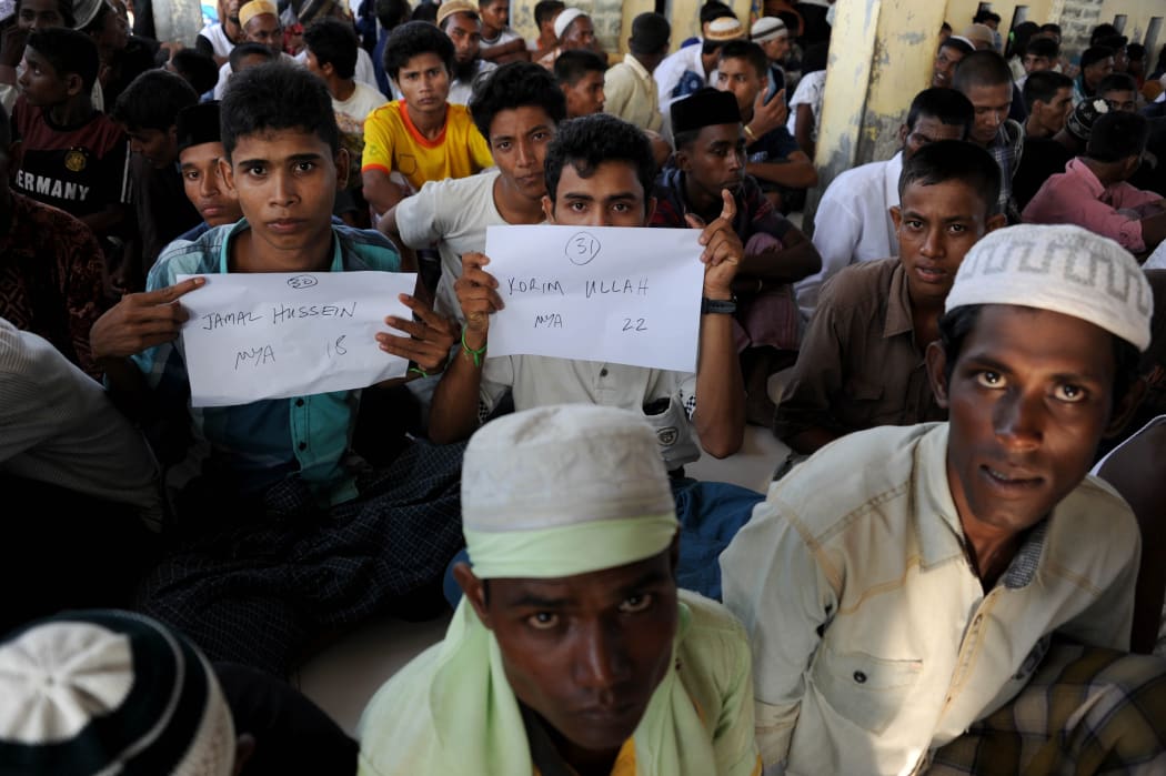 Rescued Myanmarese, part of a group of mostly Rohingyas from Myanmar and Bangladesh, prepare for a photographic identification procedure by an Indonesian immigration official in Aceh.