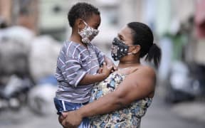 Brazilian Juliene Maria Conceicao, who is hearing impaired, holds her son, Leonardo Moreira Conceicao, both wearing protective masks against the spread of the new coronavirus (COVID-19)  in Belo Horizonte, Brazil on May 15, 2020. -