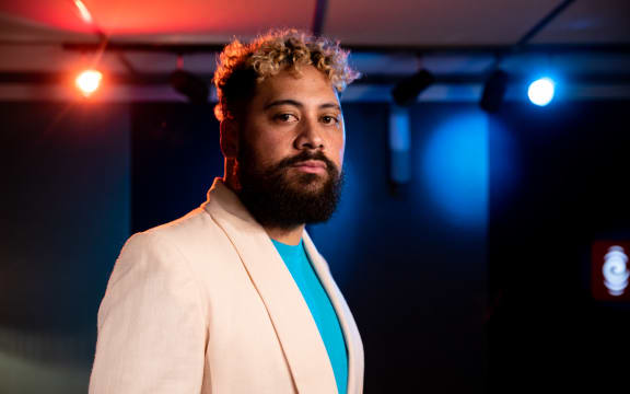 Noah Slee standing in the foreground wearing a white sports coat and azure shirt