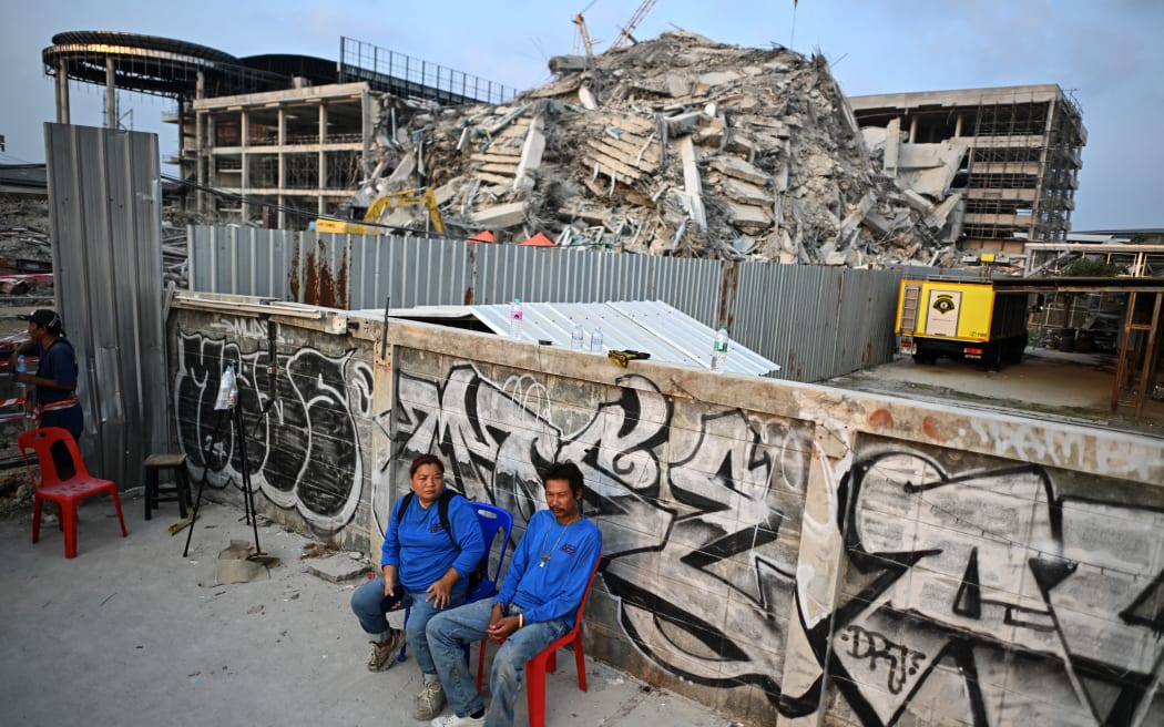 Construction workers, including Chanpen Kaewnoi (L), wait for news of missing relatives and co-workers at the site of an under-construction building collapse in Bangkok on March 29, 2025 a day after an earthquake struck central Myanmar and Thailand. A huge earthquake hit Myanmar and Thailand on March 28, killing more than 150 people and injuring hundreds, with dozens trapped in collapsed buildings and the death toll expected to rise. (Photo by MANAN VATSYAYANA / AFP)