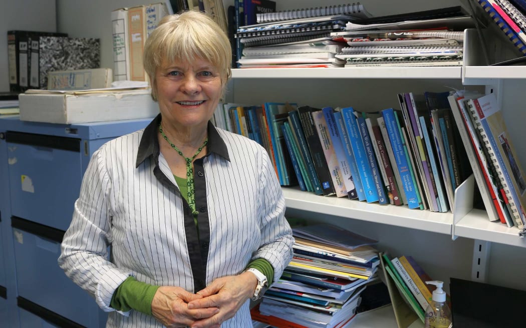 Woman stands in front of  work bookshelf