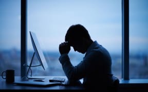 Tired or stressed businessman sitting in front of computer in office