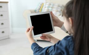 Mother and her daughter using video chat on tablet at home. Space for text