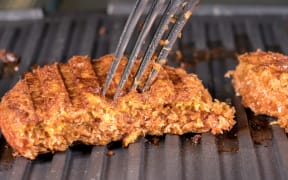 Close shot of the meat like plant-based patties for vegetarian beef burgers being grilled on hot griddle