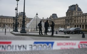 (FILES) French police officers patrol in front of the Louvre Museum after it was robbed, with the Louvre Pyramid designed by Ieoh Ming Pei in the background, in Paris on October 19, 2025. Police have arrested five new people, including a main suspect, over this month's daring jewellery theft from the Louvre museum, the Paris prosecutor said on October 30, 2025.