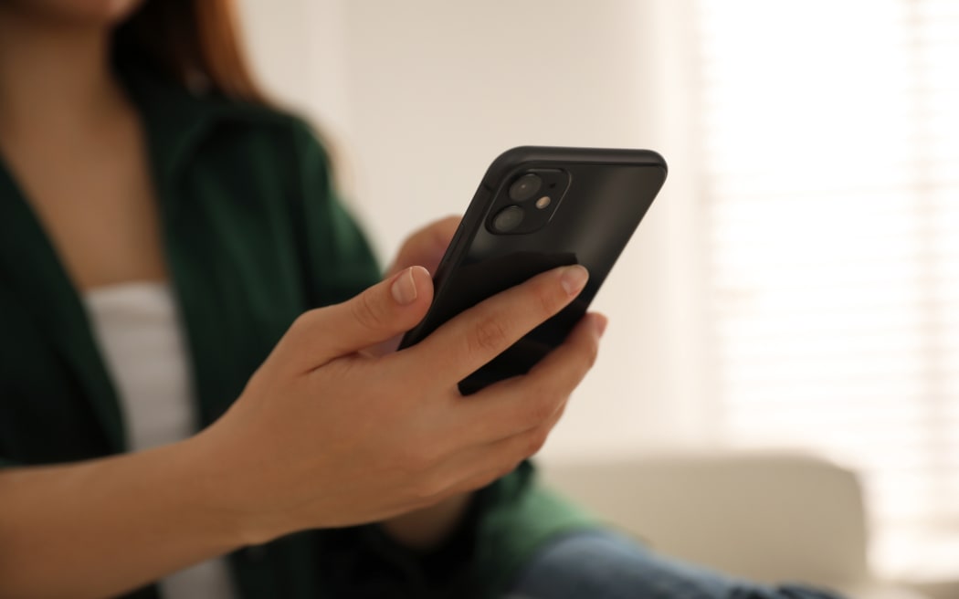 Woman holding iPhone 11 Black indoors, closeup