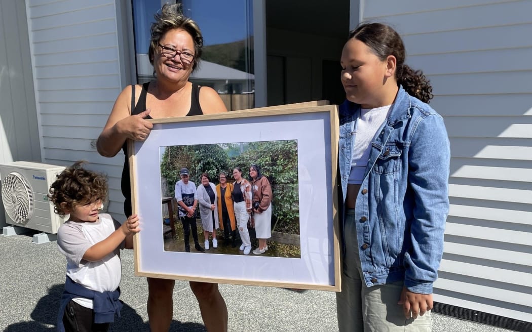 Lena Bennett and her moko about to put a whānau photo on the wall of their new home.