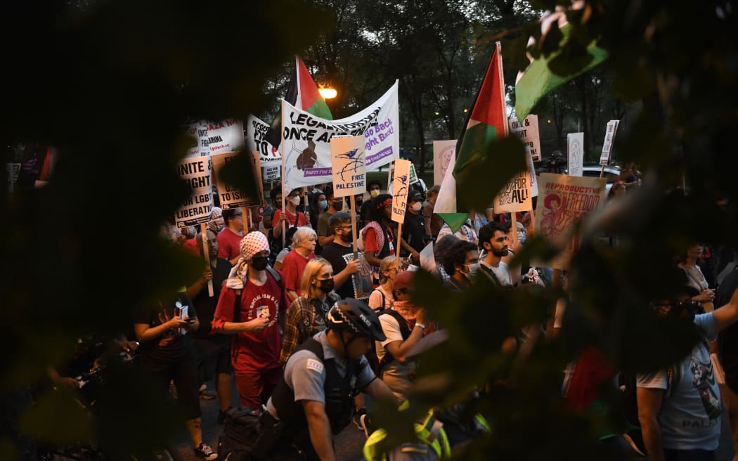 Personas sostienen banderas, pancartas y carteles palestinos durante una protesta que exige un alto el fuego en Gaza, justicia reproductiva, los derechos de las personas con discapacidades y las personas queer, antes de la Convención Nacional Demócrata (DNC) en el United Center en Chicago, Illinois. El 18 de agosto de 2024. (Foto: MATTHEW HATCHER / AFP)