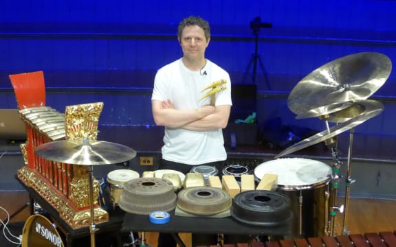 percussionist Justin DeHart posing behind a battery of his instruments