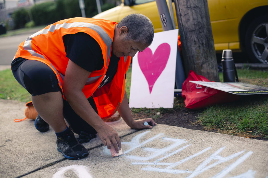 Leona Tavua, of the Auckland Save Movement, writes 'animal lives matter' on the pavement outside a Henderson slaughterhouse.