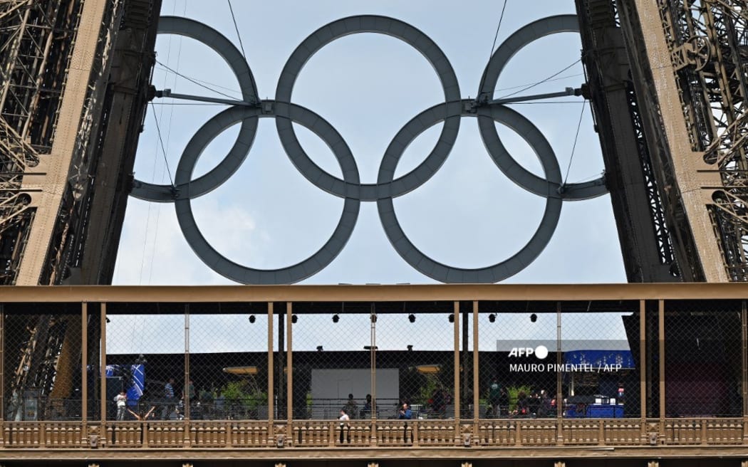 The Olympic rings are seen on the structure of the landmark as people walk on the first floor of The Eiffel Tower in Paris on July 24, 2024, ahead of the Paris 2024 Olympic Games.