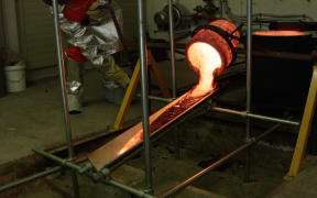 Molten lava pouring out the crucible down the tilted metal plate and beginning to cool down.