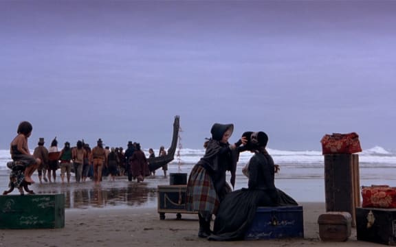 In a still image from Jane Campion's The Piano, Ada and Flora are waiting on the beach to be transported to Nelson by Māori waka.