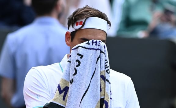 Switzerland's Roger Federer uses a towel during a break in play against Poland's Hubert Hurkacz during their men's quarter-finals match on the ninth day of the 2021 Wimbledon Championships at The All England Tennis Club in Wimbledon, southwest London, on July 7, 2021.