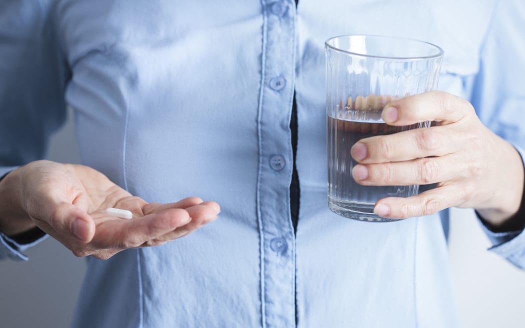 Woman taking medication with a glass of water. (Photo by CRISTINA PEDRAZZINI/SCIENCE PHOT / CPD / Science Photo Library via AFP)