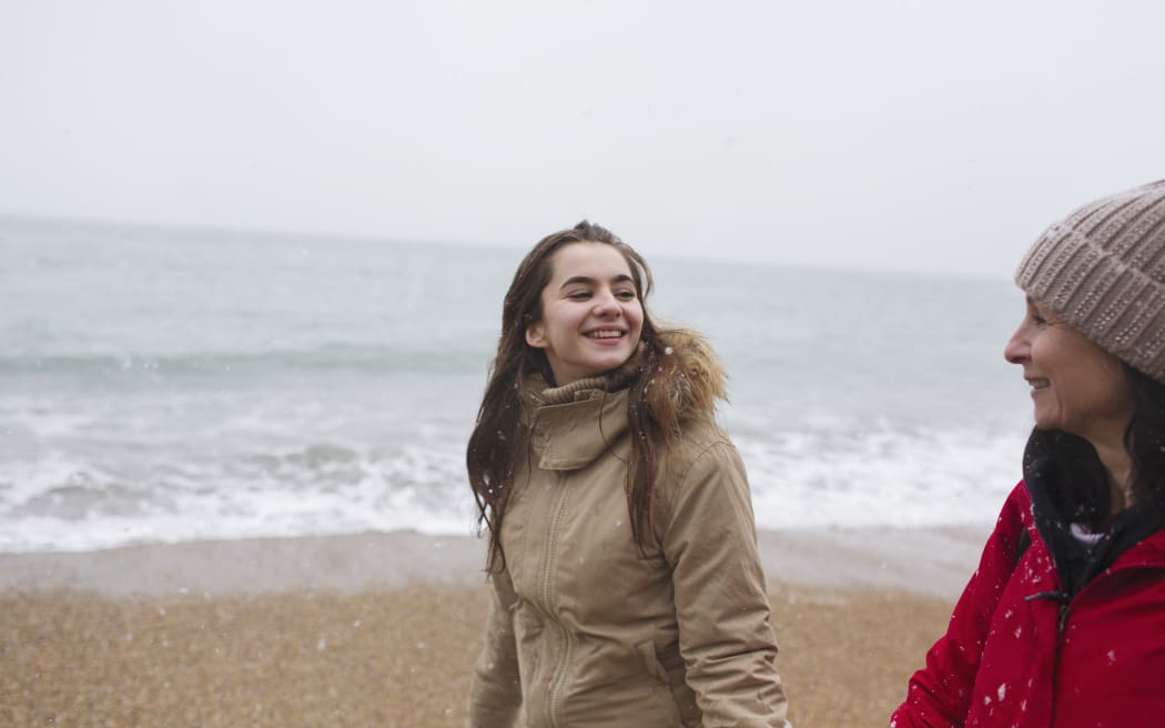 Mother and daughter in warm clothing walking on winter ocean beach. (Photo by CAIA IMAGE/SCIENCE PHOTO LIBRARY / NEW / Science Photo Library via AFP)