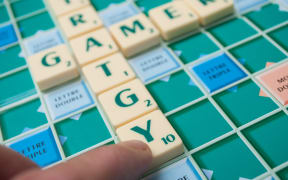 Closeup of plastic letters on Scrabble board game forming the words : Strategy and gamer.