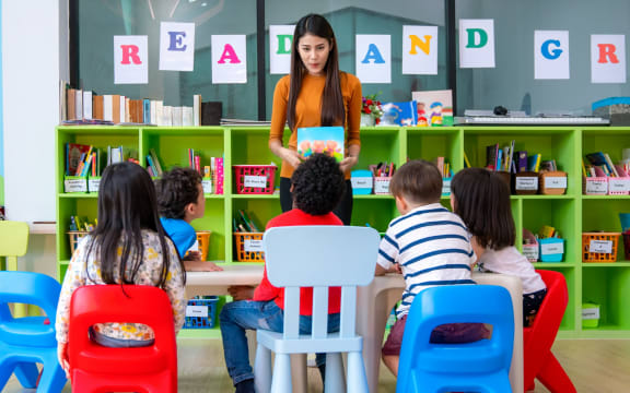 Preschool children listening to a teacher read a story