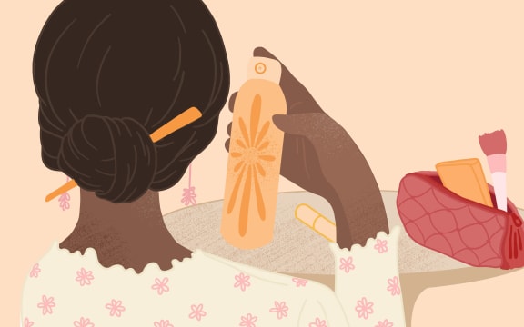 A woman holds up a spray can from a bag of cosmetics.