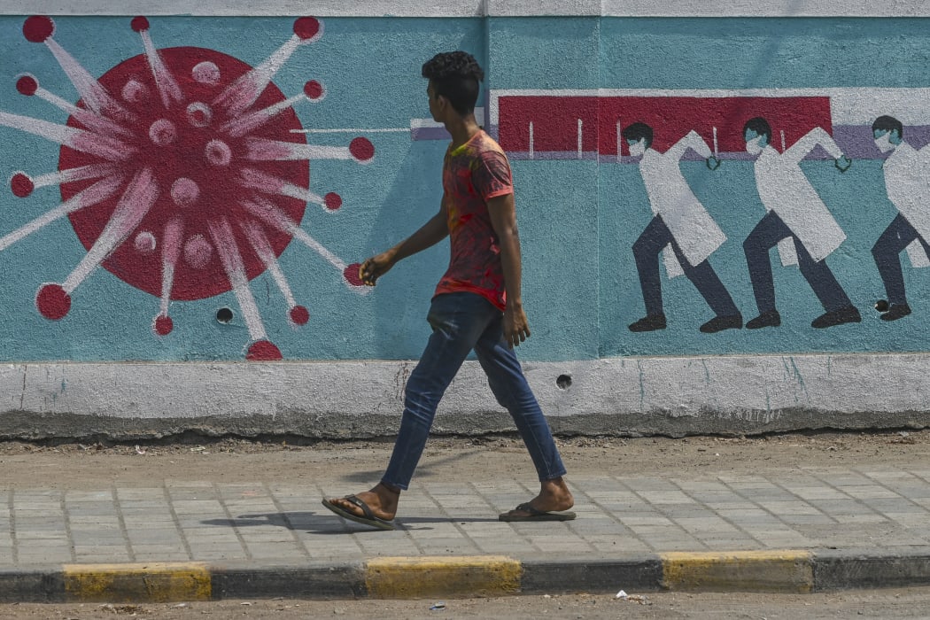 A pedestrian walks past a wall mural depicting medical staff as frontline Covid-19 warriors in  Mumbai on March 29, 2021.