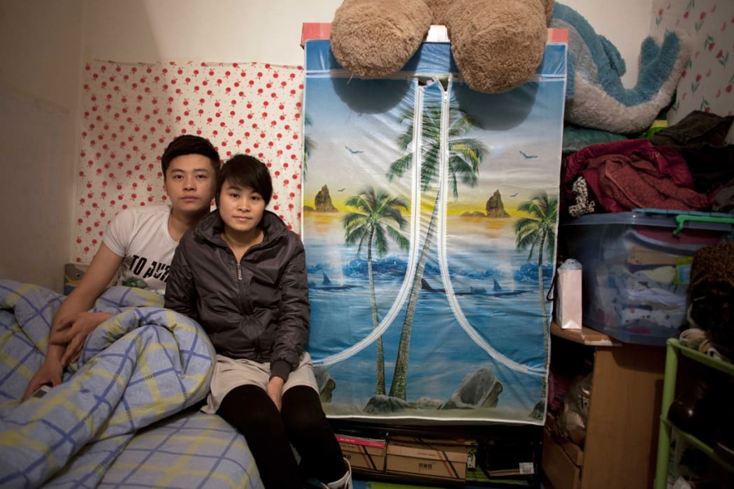 Zhuang Qiuli and her boyfriend Feng Tao sit on the bed in their basement apartment in Beijing.