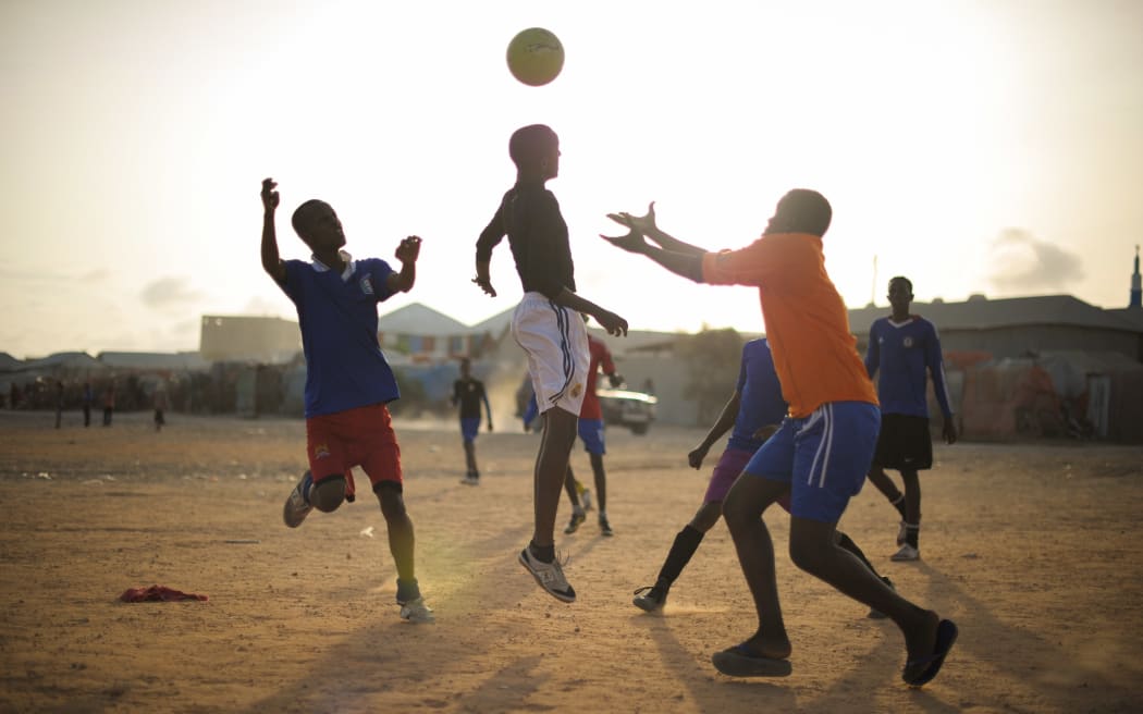 Youths playing football on dusty field in Africa