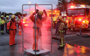 Firefighters take part in a chemical spill exercise in Kerikeri in 2020. A firefighter stands under a makeshift shower to wash off "chemicals."