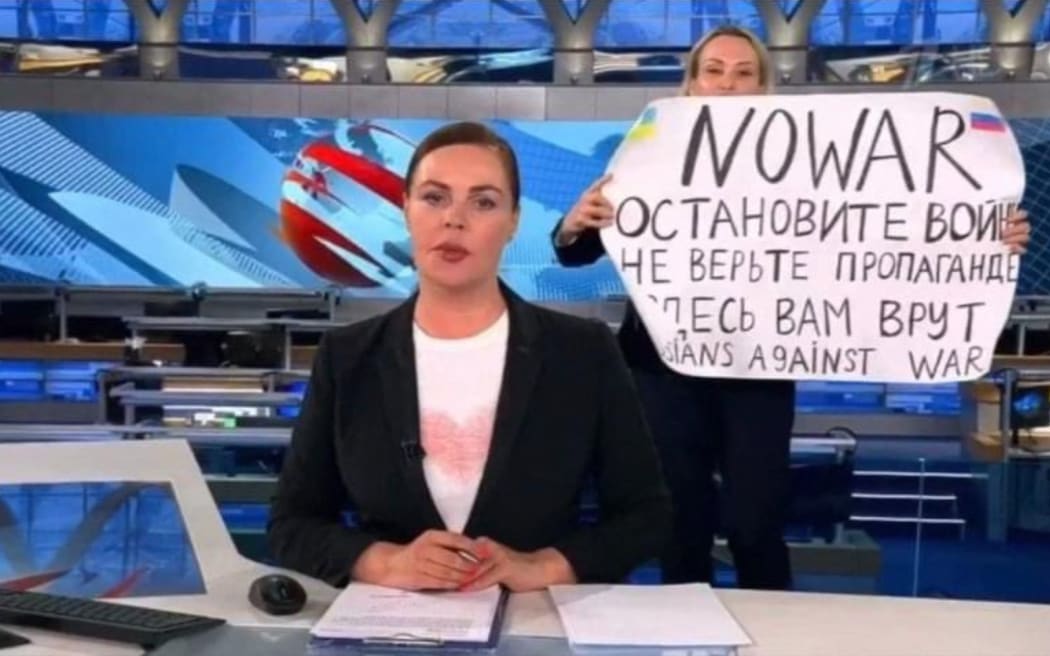 This video grab taken on March 15, 2022 shows Russian Channel One editor Marina Ovsyannikova holding a poster which reads "Stop the war. Don't believe the propaganda. Here they are lying to you" during an on-air TV studio news broadcast, in Moscow on 14 March, 2022 .