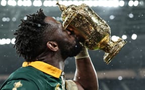South Africa's flanker and captain Siya Kolisi (C) kisses the Webb Ellis Cup as he celebrates winning the France 2023 Rugby World Cup final match against New Zealand at the Stade de France on 28 October, 2023.