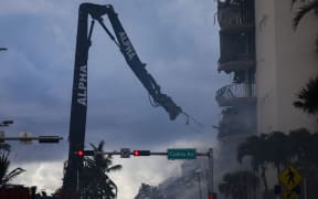 A crane removes wreckage of a partially collapsed building in Surfside north of Miami Beach, Florida on June 25, 2021. -