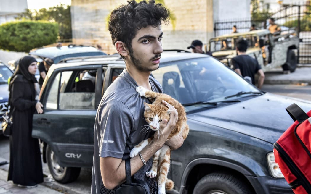 A youth holds a cat to his chest as people who fled their villages in southern Lebanon are received at an art institute transformed to shelter for persons displaced by conflict, in Beirut on September 23, 2024. Israeli air strikes killed 274 people, including 21 children, in south Lebanon on September 23, the Lebanese health minister said, in by far the deadliest cross-border escalation since war erupted in Gaza on October 7. (Photo by FADEL ITANI / AFP)