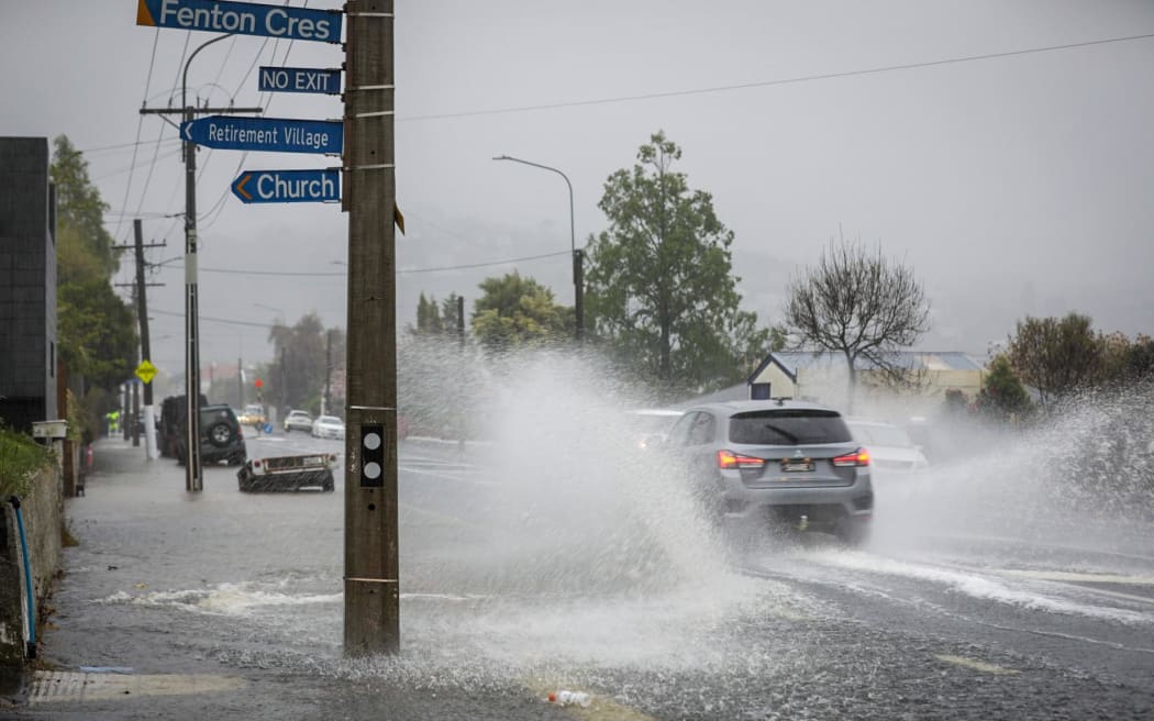 A car ploughs through surface flooding on a Dunedin street on 3 October 2024.