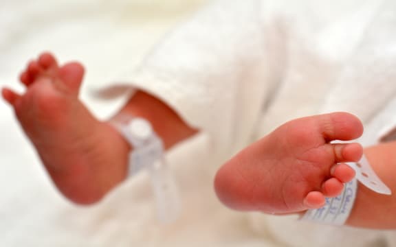 Newborn baby feet with identification bracelet tag name.