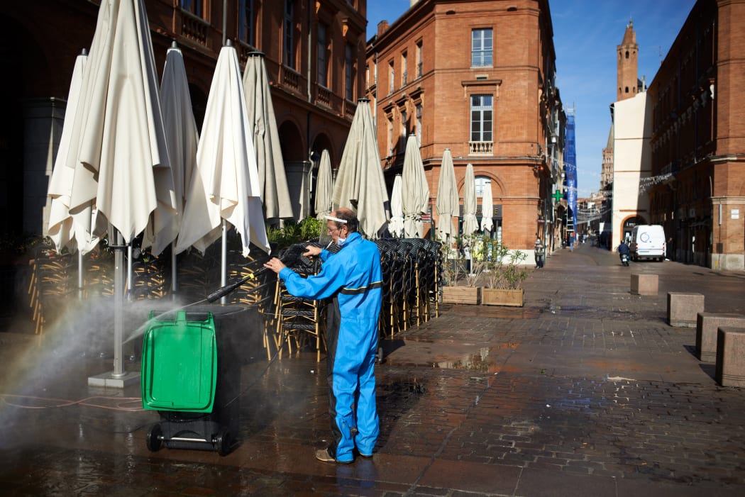 A worker cleans a bin in front of a closed cafe in Toulouse, on the second day of France's new lockdown.