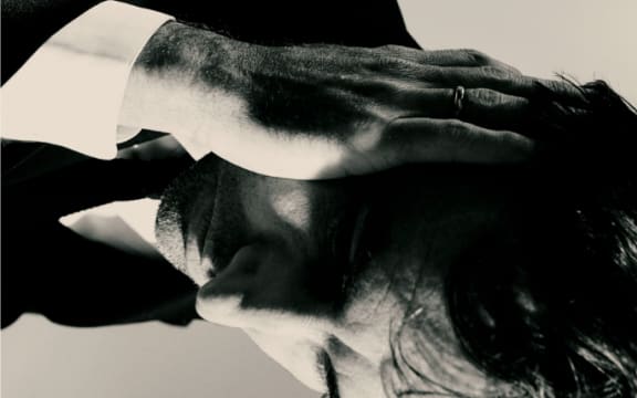 Cover image of Andrew Bird's album 'Inside Problems'. Portrays Bird on his side with hand to head.