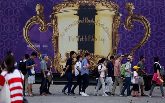 Rugby fans pose in front of a Web Ellis Cup banner outside the City of Toyota Stadium on September 23, 2019.